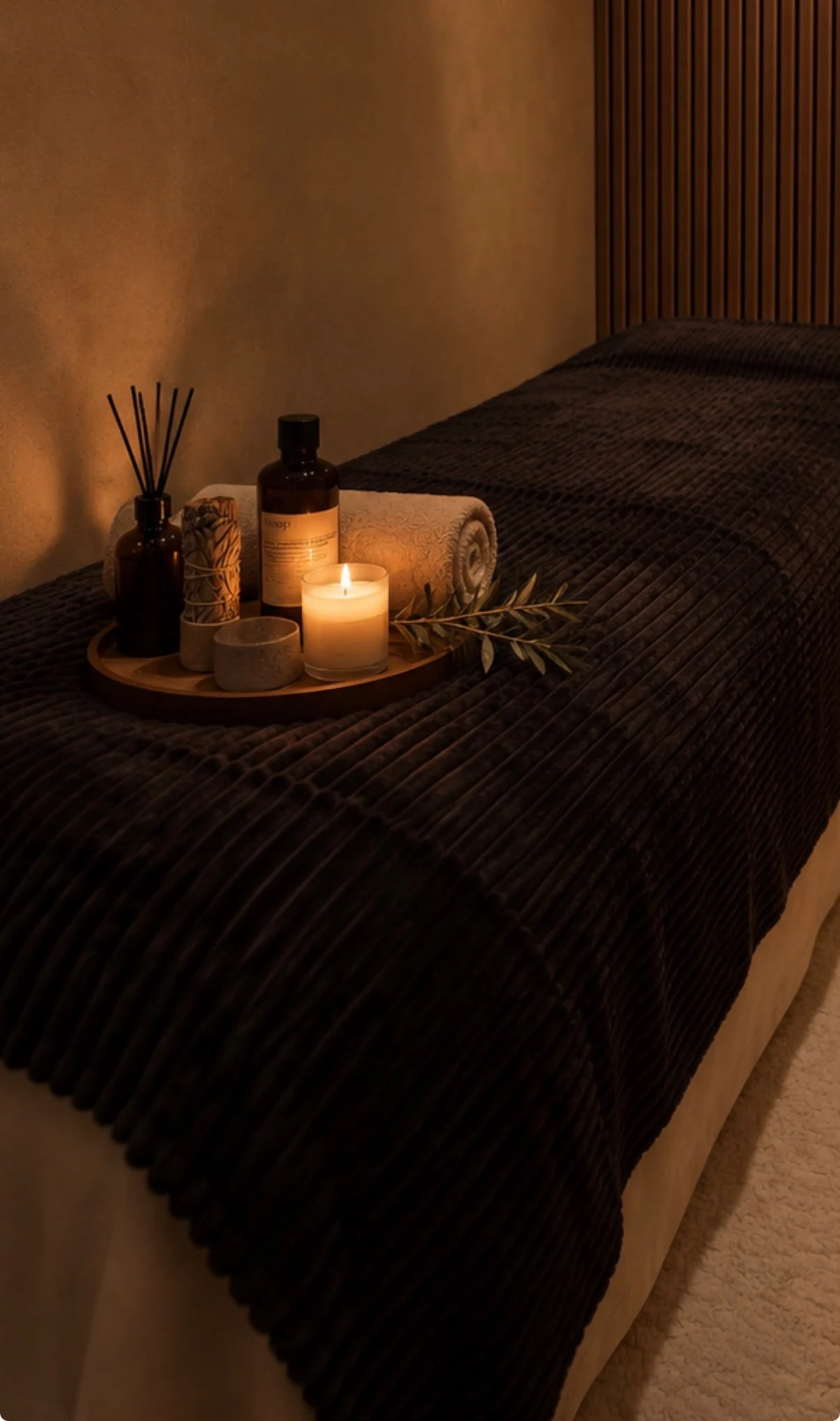 Padded table prepared with oils, towels, and a candle